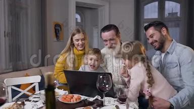 幸福快乐的家庭在电脑上观看美丽的照片，这些照片显示他们尊敬的<strong>老爷爷</strong>坐在一起