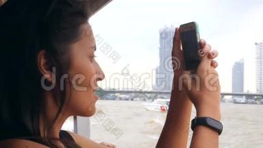 年轻的混合种族旅游女孩在泰国小船上巡游，并使用手机拍照。 泰国曼谷。 4K