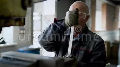年龄大的男工正在工厂的一个车间里<strong>调整机器</strong>，转动钥匙，用锤子