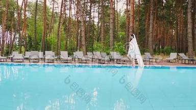 戴着长面纱的新娘在游泳池里走来走去。 豪华酒店的婚礼
