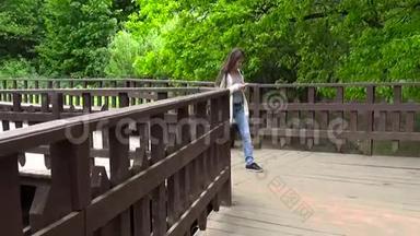 少女在木桥上用手机.. 年轻人在智能手机上发短信。 运动摄像机
