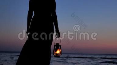 穿着裙子的孤独女人拿着煤油灯，看着夕阳的天空背景