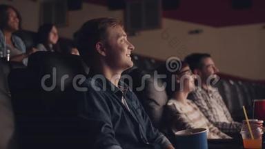 在电影院看电影的年轻人一边看电影一边吃着烤饼，一边笑