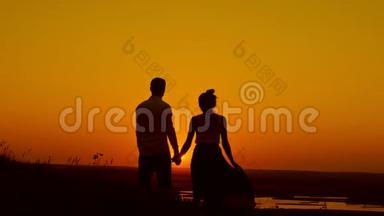 在<strong>夕阳</strong>下，可爱的一对情侣-年轻的男人和美丽的女孩站在<strong>夏日</strong>的草地上，望着阳光，剪影