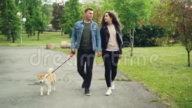 多莉拍摄的欢乐人群学生在城市公园遛狗，盖伊牵着狗，抱着他女朋友的