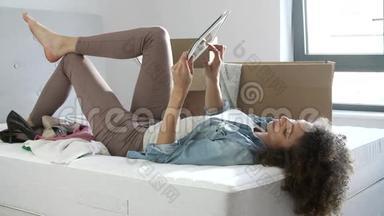 使用<strong>数码</strong>平板电脑躺在床上的妇女进入新<strong>家</strong>