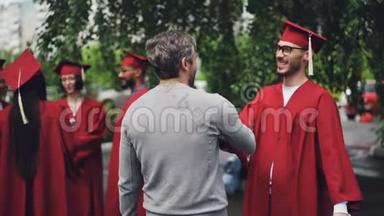 大学教授在毕业典礼结束后祝贺他的学生拥抱他，握手，老师感到骄傲