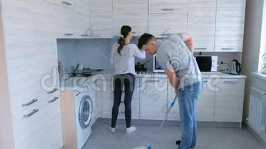 <strong>夫妻</strong>俩<strong>一起</strong>在厨房打扫卫生.. 男人用拖把洗地板，女人擦家具。