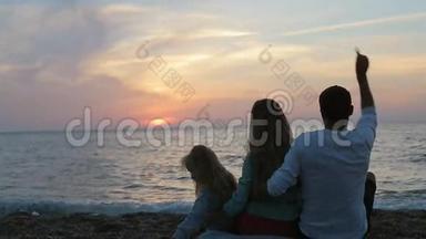 幸福的一家人坐在海边的夕阳下