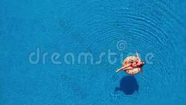 一位穿红色<strong>比基尼</strong>的<strong>女士</strong>躺在游泳池的甜甜圈上的空中景色