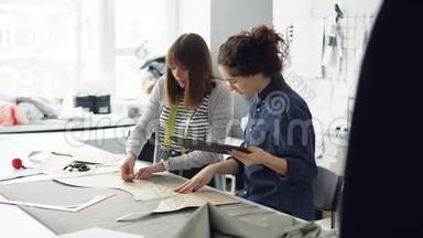 有吸引力的<strong>服装设计</strong>师企业家们正在用粉笔勾勒出剪裁，用平板电脑和谈话。 忙碌的一天
