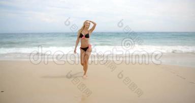 黑色比基尼的金发女人站在海滩上