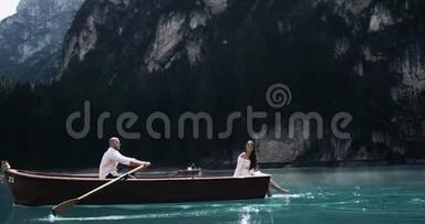 一对浪漫的<strong>情侣</strong>在湖中央的木船上和那个男人一起<strong>划船</strong>