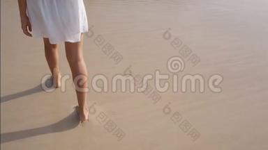 女人的腿在沙滩上留下脚印，挥手洗去脚印