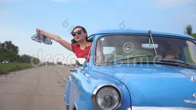 带着围巾的年轻女孩从老式汽车的车窗里探出来，享受着<strong>乘车</strong>的乐趣。 女人从复古中脱颖而出