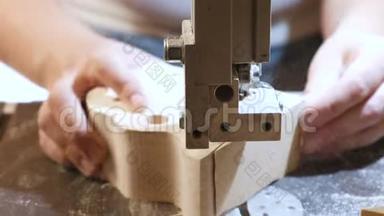 工匠正在用锯条从木头上切割一个木制工件。 <strong>特写双手</strong>。
