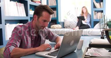 使用笔记本电脑和数码平板电脑在家庭办公室的情侣