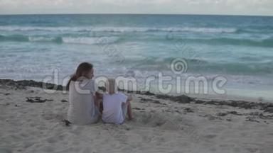 妈妈和儿子坐在海边的海滩上