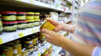 接近白种人的女人手靠近商店货架，在杂货店里选择淡蜂蜜