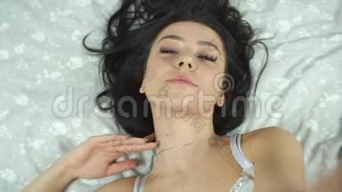 美丽的模特躺在酒店的床上，在家里在床上摆姿势拍照或自拍