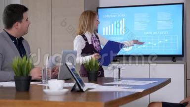 在会议室，女商人手里拿着剪贴板，展示公司的数据