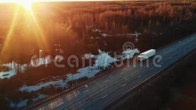 一辆半卡车在高速公路上行驶，进入日落，前视空中摄像机。