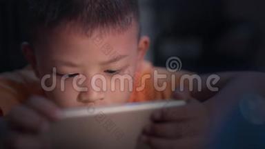 孩子<strong>玩手机</strong>，用手揉眼睛。 可爱的小男孩晚上在家<strong>玩手机</strong>游戏。