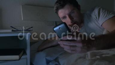 深夜在家中躺在床上的年轻人，在低光线下使用手机，在通信技术上放松