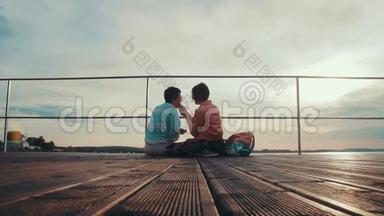 两个女朋友在坐在木墩边上的池塘边互相<strong>喂饭</strong>。 欢乐的夏日