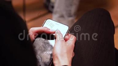 穿着黑色裤子的女孩坐着，拿着她的手机，屏幕上沾满了手指。 高清高清