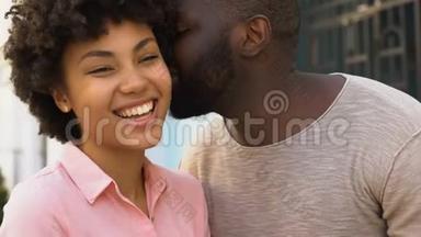 非洲男友对女朋友耳语情话，幸福的微笑情侣