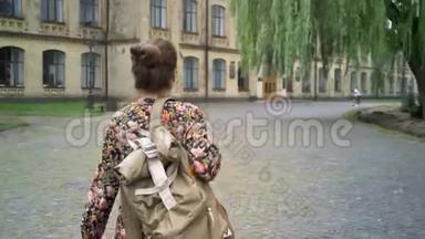 年轻开朗的女大学生背着背包上大学，走在大学附近的街道上，美丽而又美丽