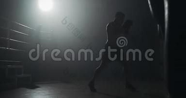 剪影拳击手在黑暗的健身房打拳。 体力锻炼。 男拳击手在黑暗中锻炼。 跆拳道剪影