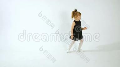 可爱的小女孩穿着黑色的裙子跳舞，玩得很开心，被隔离在白色的身上
