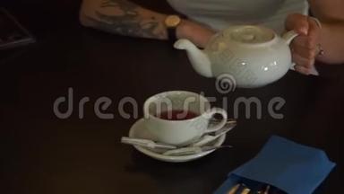 茶被倒入玻璃透明<strong>茶杯</strong>中。 一杯茶。 糖果，热茶和茶壶.. 陶瓷茶壶和玻璃<strong>茶杯</strong>特写..