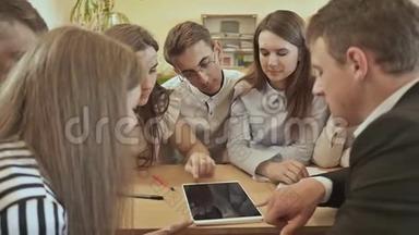 同学们围坐在课桌旁，用平板讨论学校的任务.. 俄罗斯学校。