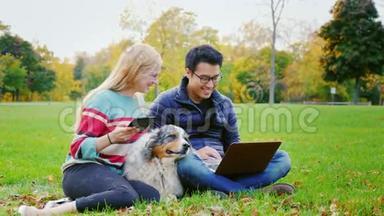 学生们在公园里放松。 亚洲男人用一个笔记本电脑女人，旁边坐着平板电脑。
