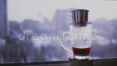 咖啡滴在杯子里，洒在窗外城市景观的背景上。 用越南语酿造咖啡。 慢慢