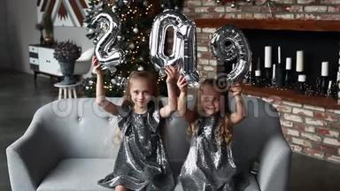 两个微笑的小女孩牵手新年`气球，。 编号2019。 圣诞节。 新年概念