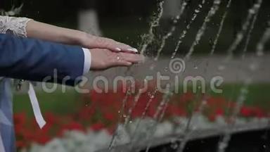 在喷泉旁的新婚夫妇的手。
