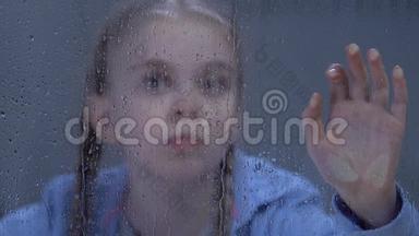 可爱的孤独的青春期女孩看着窗外的雨被雷雨吓坏了