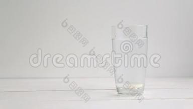 两片阿司匹林或泡腾片滴入一杯水，在白色背景上缓慢运动。