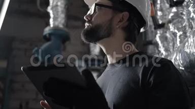 戴头盔的技术员在装有平板电脑的锅炉房工作