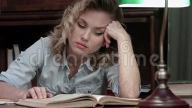 <strong>劳累</strong>了<strong>一天</strong>的年轻女子在工作后坐在桌子旁看书睡着了