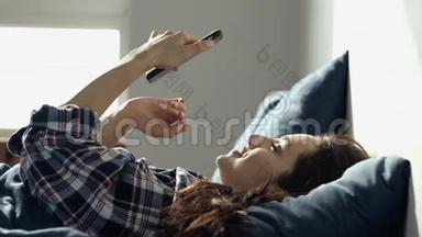 年轻女子在检疫期间呆在家里。 躺在床上使用智能手机。 发<strong>短</strong>信或打<strong>短</strong>信。 社会<strong>媒体</strong>生活
