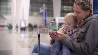 在机场带孩子的女人。 妈妈和女儿在机场休息室