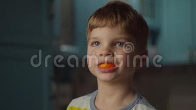 <strong>一个</strong>学龄前金发男孩在<strong>嘴</strong>里玩橘子皮。 微笑的孩子<strong>嘴</strong>里有橘子水果。 橙色