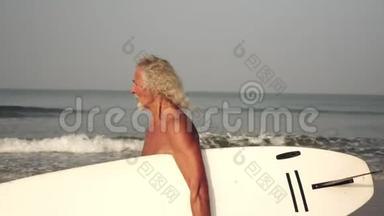 成熟的白发男人正在冲浪。 有冲浪板的老头。 在职体育退休人员