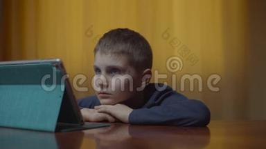 自闭症男孩使用平板电脑坐在办公桌前的肖像。 家里有小玩意的自闭症孩子。 自闭症