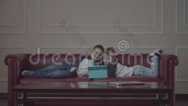两个<strong>兄弟</strong>穿着同样的衣服，用小玩意躺在家里的沙发上。 小<strong>兄弟</strong>在沙发上看着一台平板电脑。
